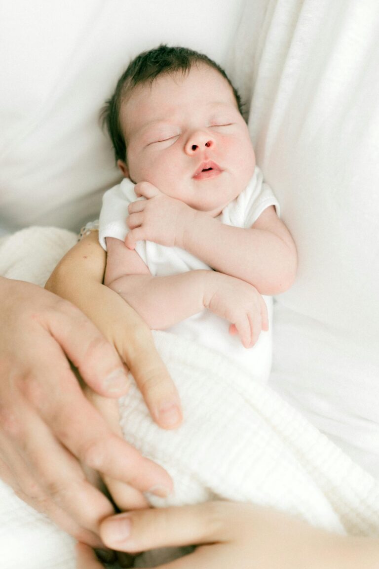 A peaceful newborn baby sleeping in a parent's protective arms, symbolizing love and security.