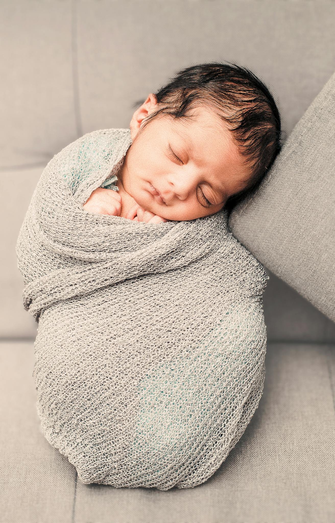 A peaceful newborn baby wrapped in a soft, cozy blanket, sleeping soundly indoors.